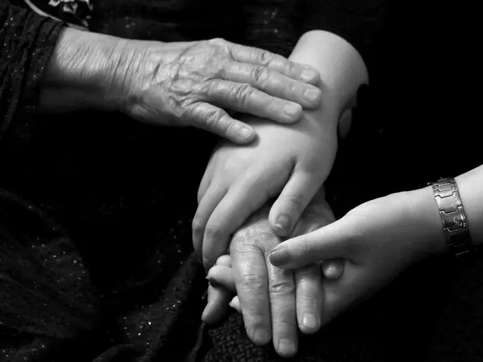 Two people holding hands, in black and white